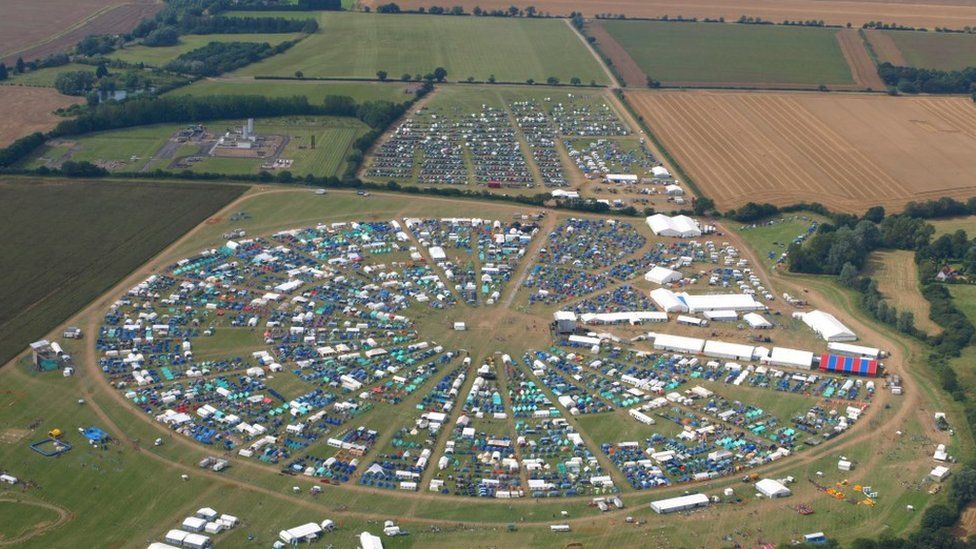 Aerial view of the event in 2012, shows tents and cars arranged within a circular perimeter on a field.