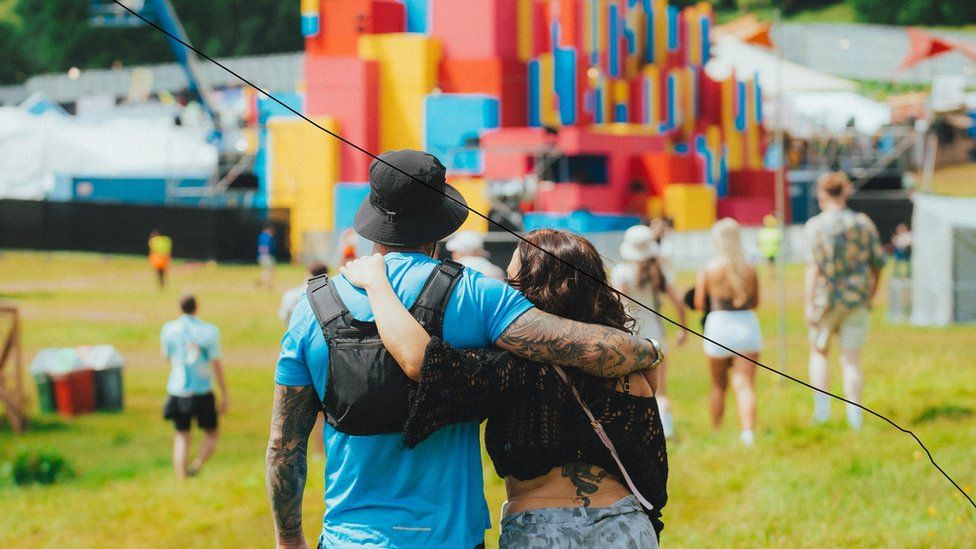 A couple walk arm in arm towards one of the main stages at Love Saves The Day in Bristol
