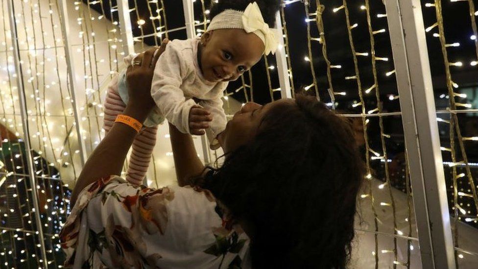 A woman plays with her baby around light decorations in Lagos, Nigeria December 30, 2023.