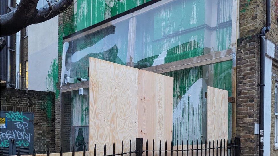 The mural covered with plastic and surrounded by wooden boards