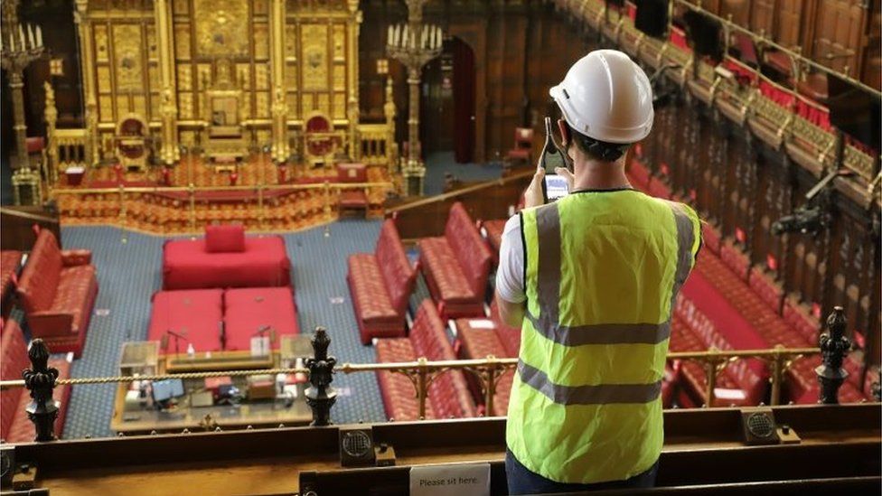 A man with a hard hat and hi-vis clothing looking into the chamber of the House of Lords