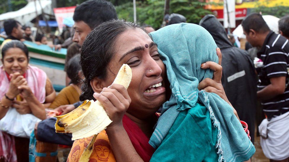A woman cries as she holds her son after they were evacuated from a flooded area in Aluva - 18 August