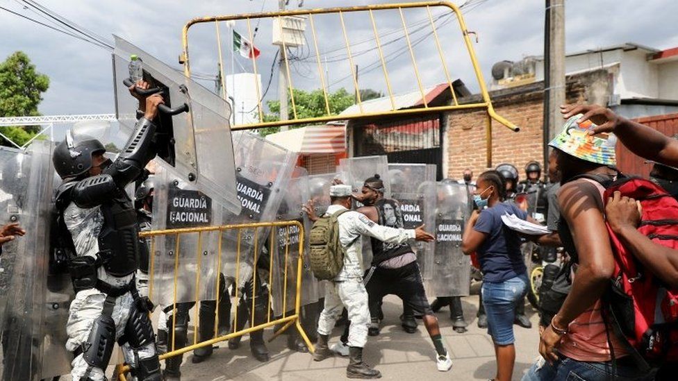 Migrants throw a fence toward police officers in riot gear during a protest to demand speedy processing of humanitarian visas to continue on their way to the United States, outside the office of the National Migration Institute (INM) in Tapachula, Mexico February 22, 2022.