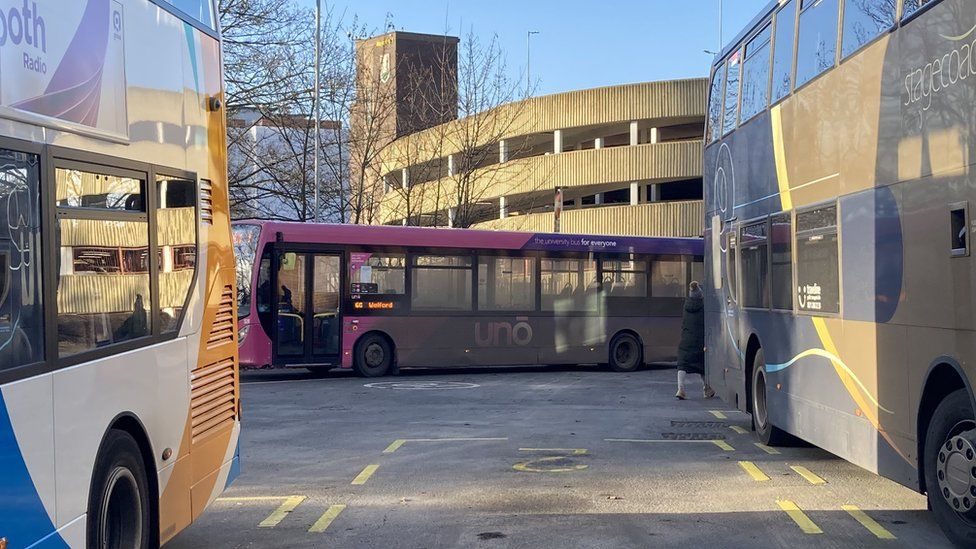 A purple Uno bus pulls out of a bus station