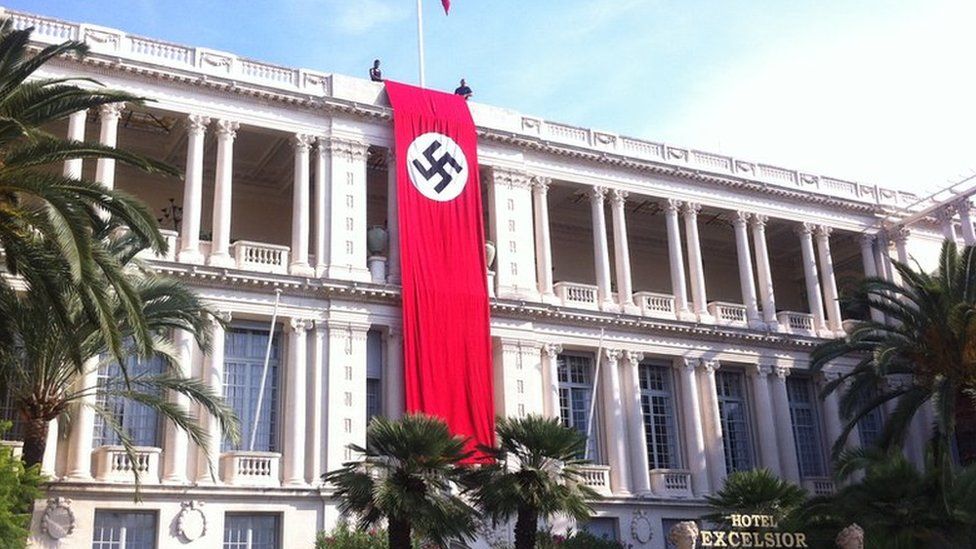 Two men hold Nazi banner over facade of the Palais de la Prefecture in Nice on Monday 28 September