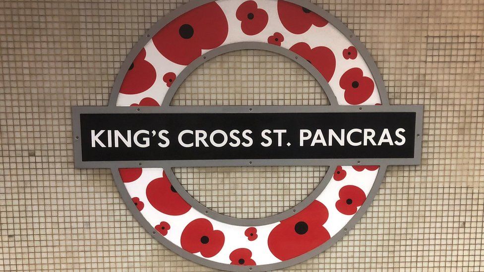 A London Underground roundel is modified with poppies, at King"s Cross St Pancras station