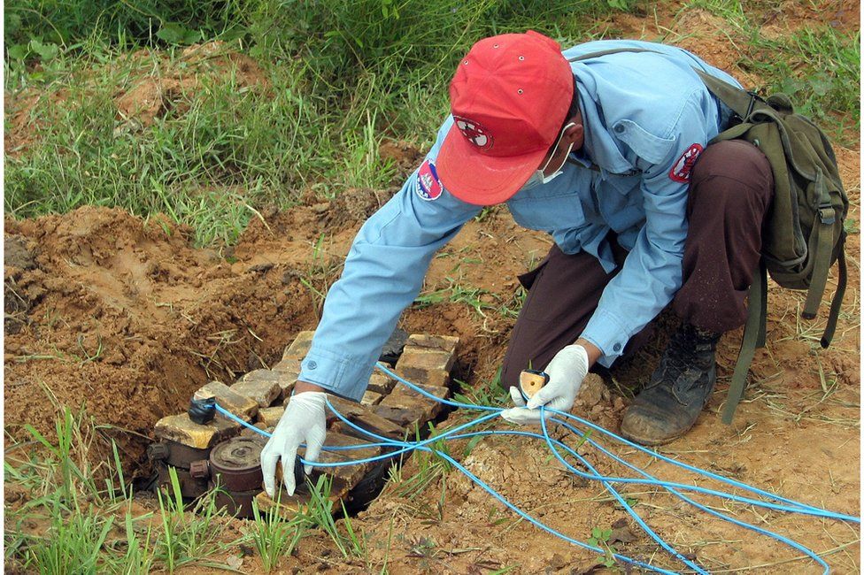A de-miner from the Cambodian Mine Action Center sets charges on a pile of landmines seized from a scrap yard in 2006