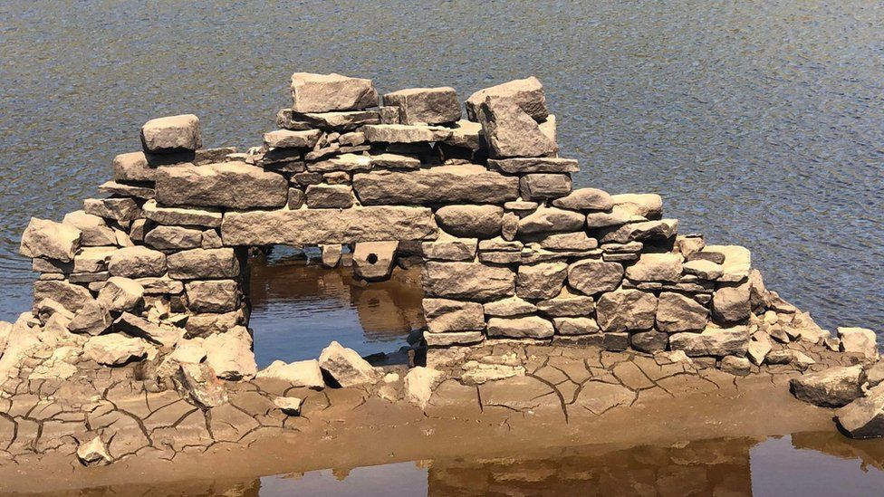 An old structure emerging from a water reservoir.