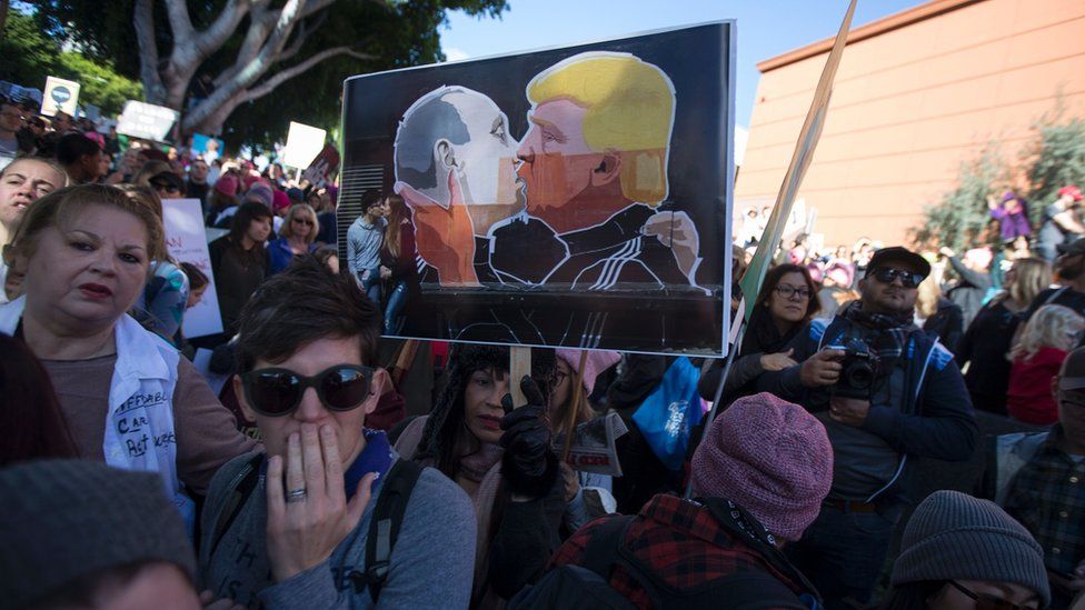 A marcher carries a picture depicting Russian president Vladimir Putin (L) and U. president Donald Trump kissing during the Women's March on January 21, 2017 in Los Angeles.