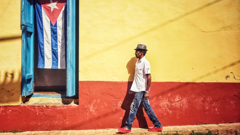 A man walks past a Cuban flag in Trinidad