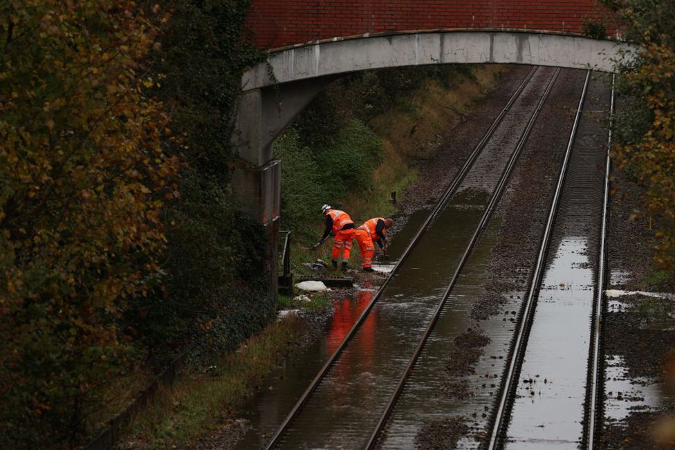 Workers evacuate the water over the flooded railway in Romsey, southern England