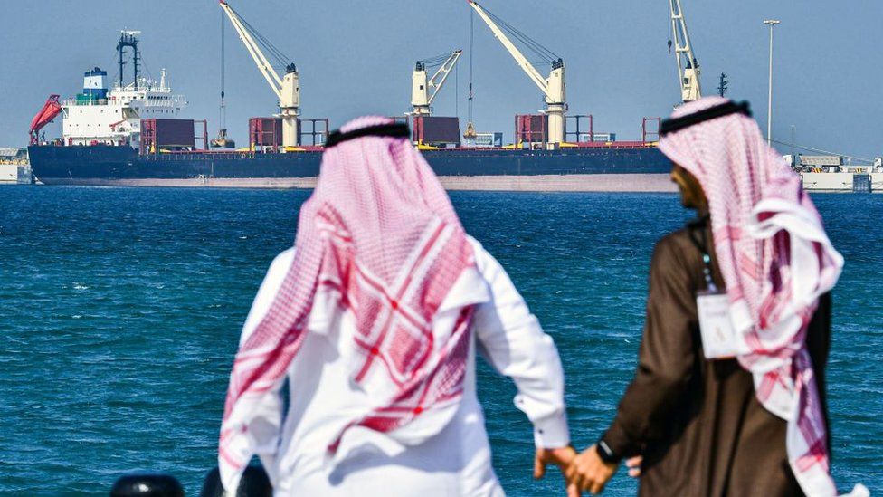 Two men in Saudi Arabia stand in front of an oil tanker