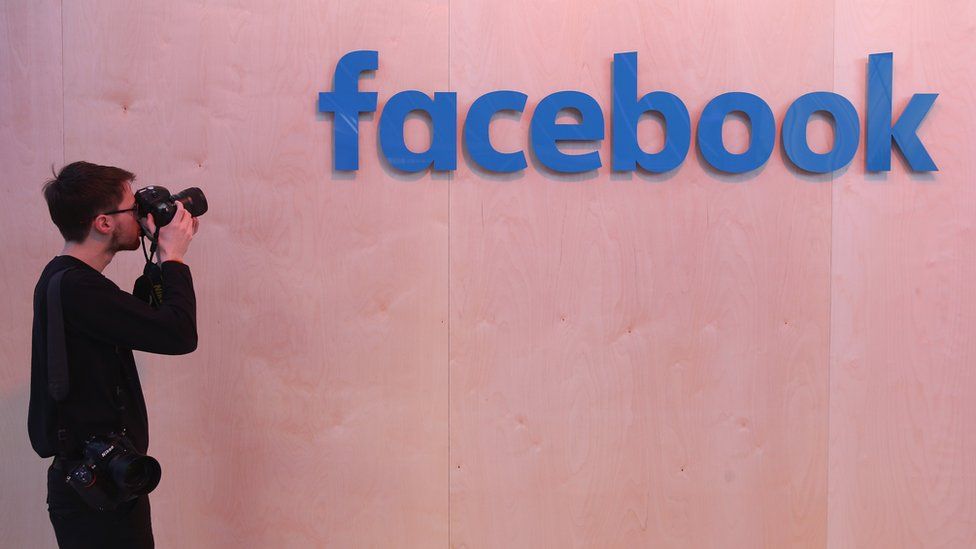 A photographer snaps a photo of the Facebook logo at the Facebook Innovation Hub on February 24, 2016 in Berlin, Germany.