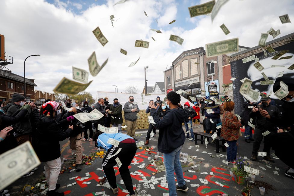 Banknotes are thrown into the air as people react after the verdict in the trial of former Minneapolis police officer Derek Chauvin, at George Floyd Square in Minneapolis, Minnesota, 20 April 2021