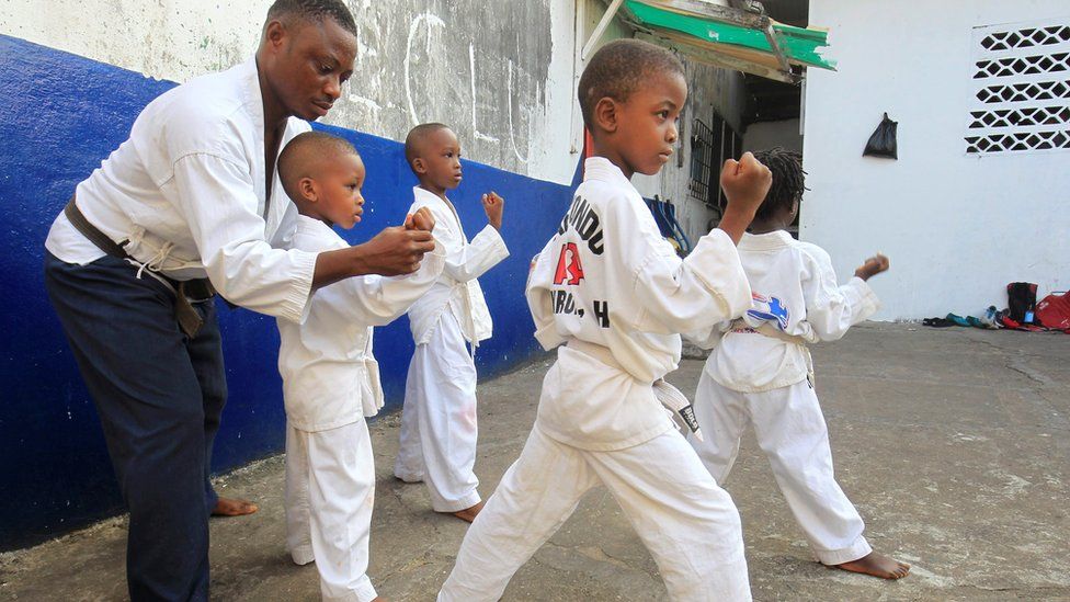 Group of four young boys dress in martial arts garb learn taekwondo from an instructor in Monrovia, Liberia - Sunday 20 November 2016