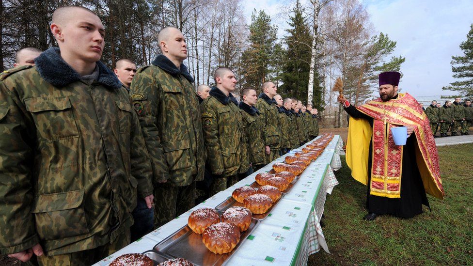 A priest blesses easter cakes and Belarusian soldiers during an Orthodox Easter ceremony