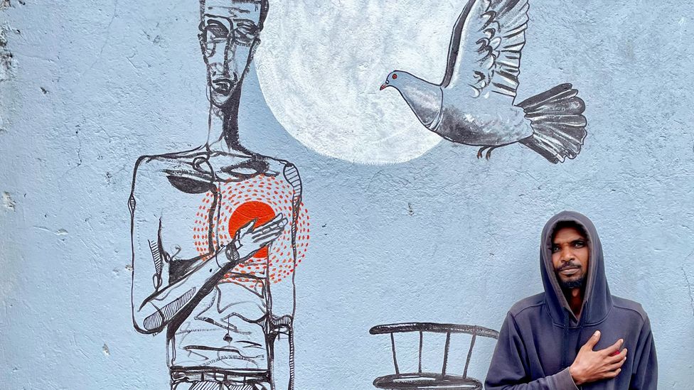 Galal Yousif next to his mural Man With a Heavy Heart in Addis Ababa, Ethiopia