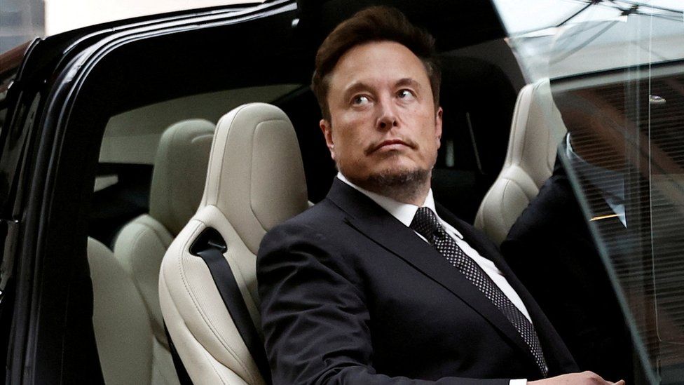 Генеральный директор Tesla Илон Маск садится в автомобиль Tesla, когда выходит из отеля в Пекине, Китай.