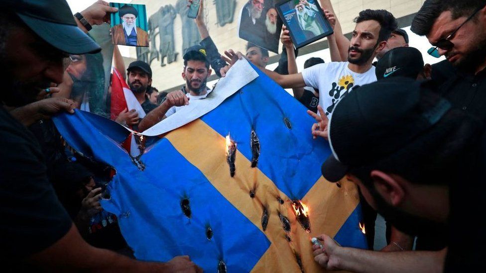 Supporters of the former paramilitary group Hashd al-Shaabi burn a Swedish flag during a protest in Baghdad's Tahrir square on July 20, 2023
