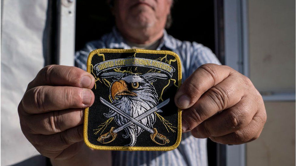 A member of United Constitutional Patriots New Mexico Border Ops militia team shows their group's patch outside their camper in Anapra, New Mexico on March 20, 2019.