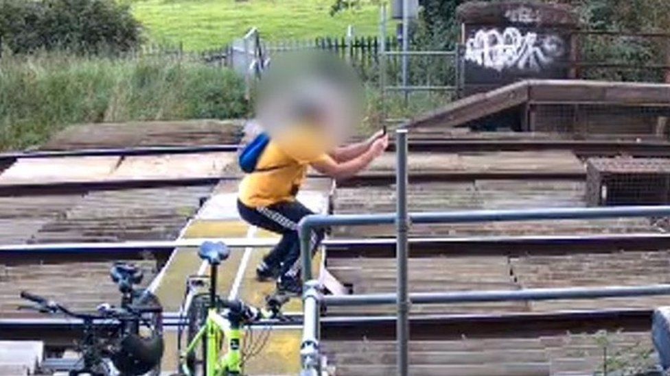 person holding camera on train tracks