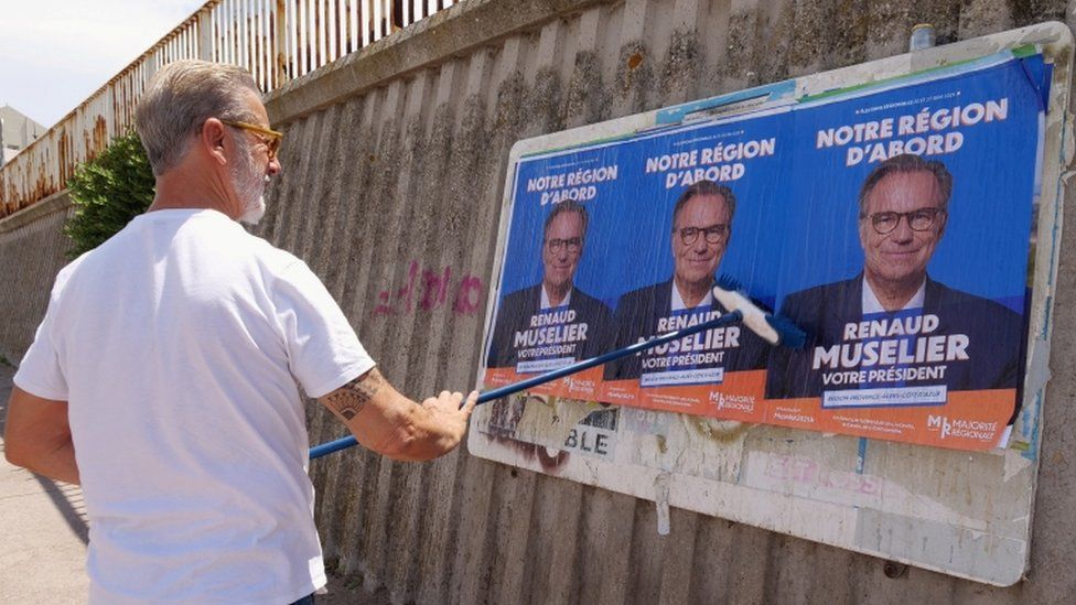 Мужчина наклеивает плакаты члена консервативной партии Les Republicains (LR) Рено Мюзелье на рекламный щит в Марселе