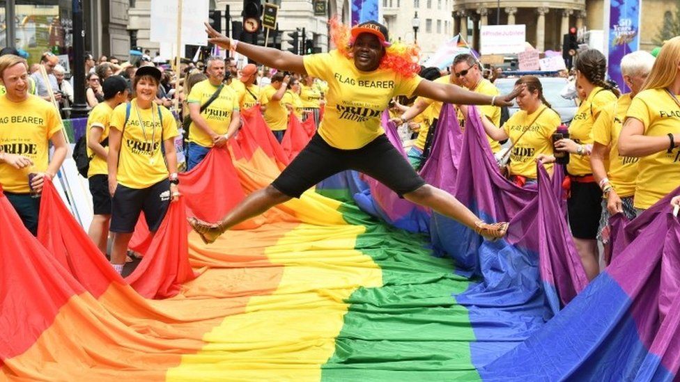 Flag bearer jumps over a rainbow flag at London's Pride event