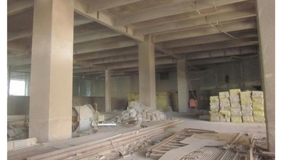 The inside of the building shows dusty floors and construction materials