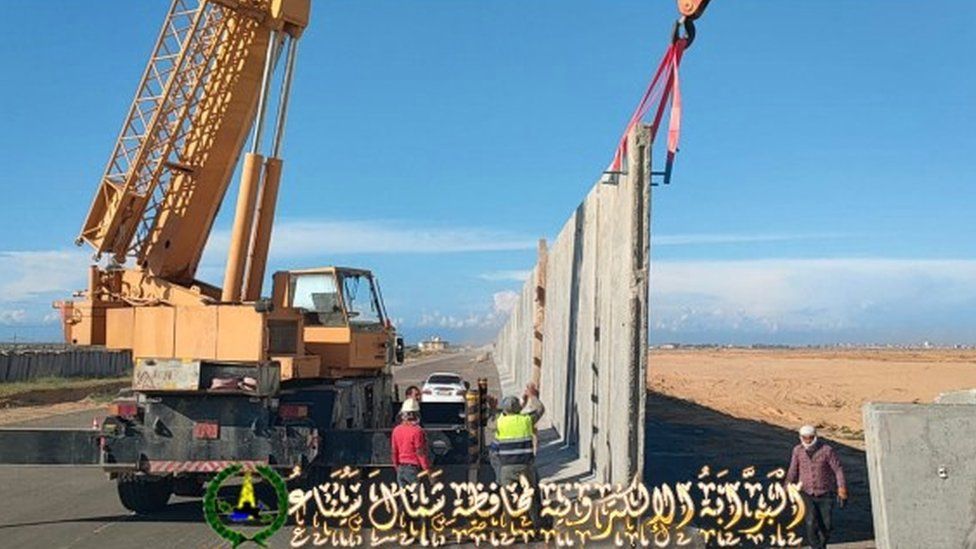Pictures show the erection of a wall around the cleared site