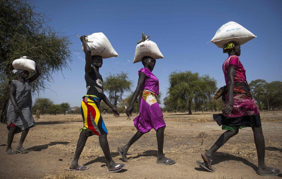 Women carry food in gunny bags after visiting an aid distribution centre in Ngop in South Sudan"s Unity State on March 10, 2017. The Norwegian Refugee Council (NRC) distributed food (maize, lentils, oil and corn soya blend) for more than 7,100 people in Ngop. South Sudan,