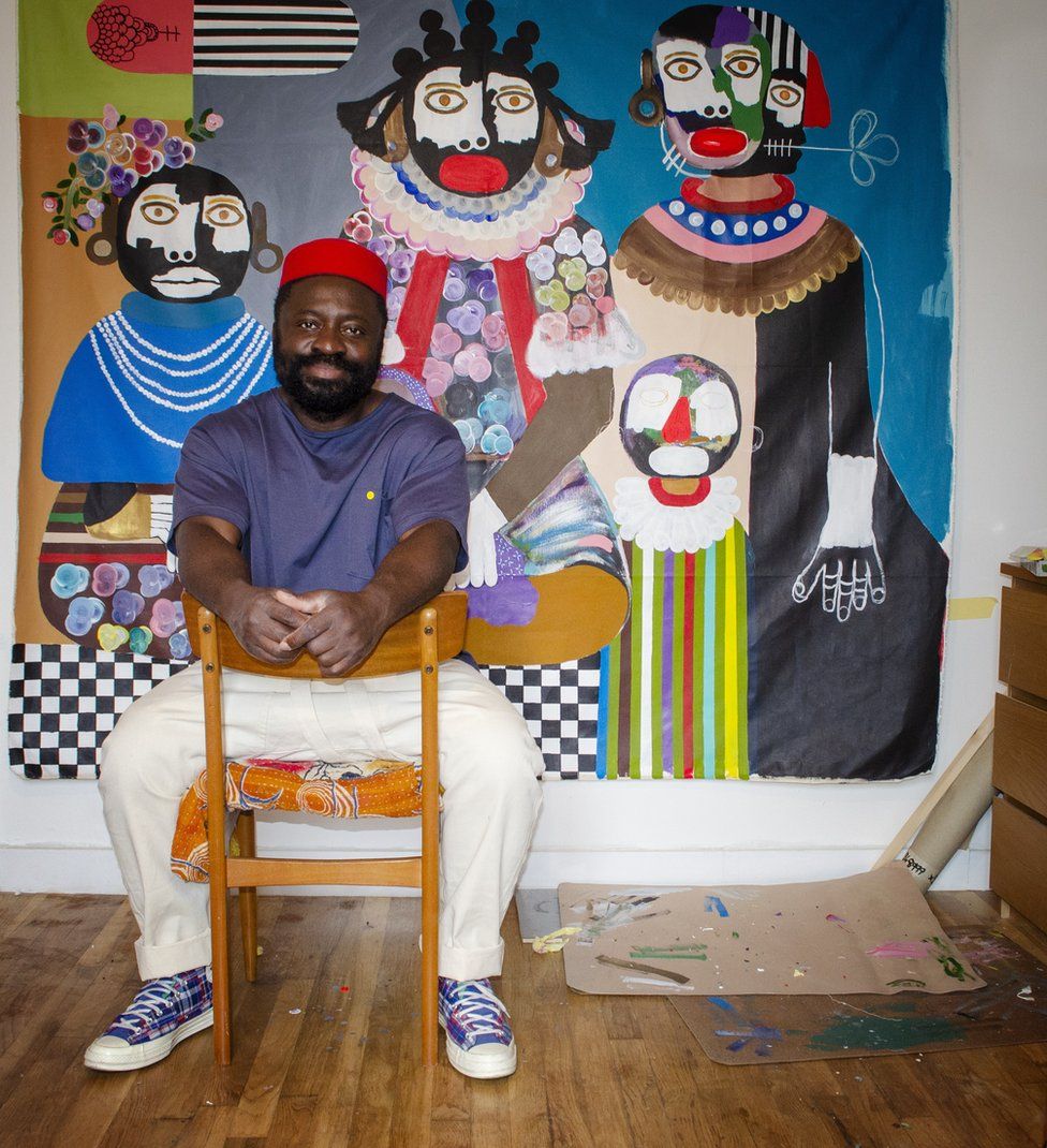 Kojo Marfo poses in his studio in front of one of his paintings