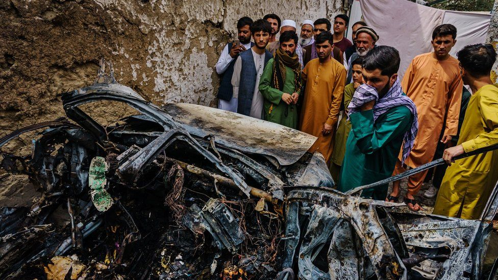 Relatives and neighbors of the Ahmadi family gathered around the incinerated husk of a vehicle targeted and hit by an U.S. drone strike that was supposed to target ISIS-K suicide bombers but instead killed 10 civilians including 7 children, in Kabul, Afghanistan, Monday, Aug. 30, 2021