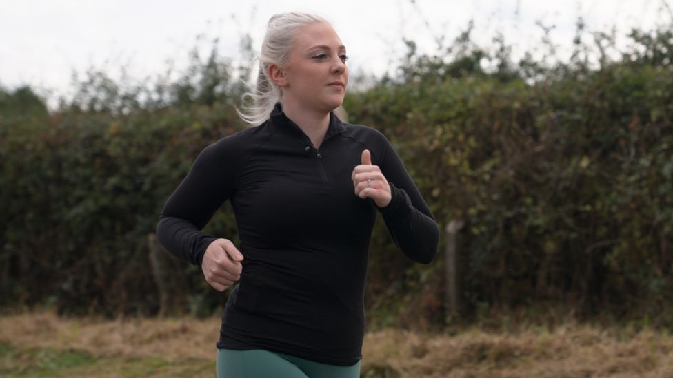 Woman in running gear runs through a field