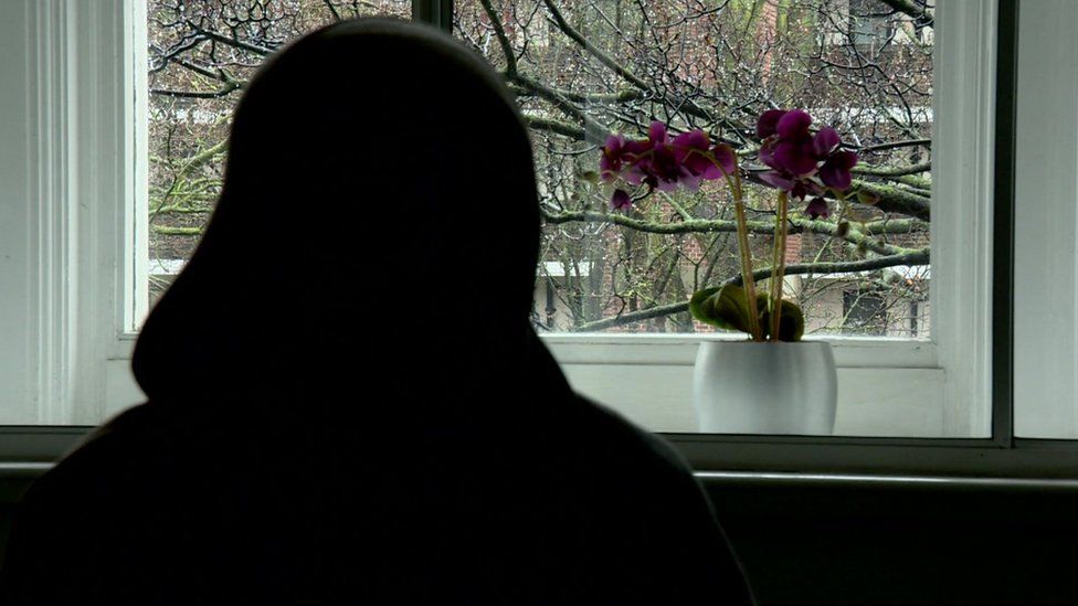 'Sarah', an anonymised woman photographed in silhouette with a purple orchid plant in the background