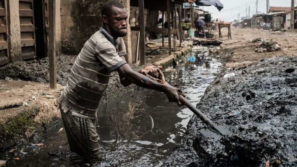 A man removes sludge from a ditch to improve the drainage system in the Mosafejo area of Lagos on February 12, 2019