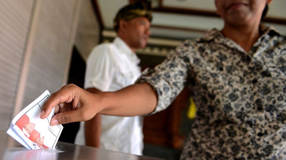 A Balinese woman casts her ballots at a polling station in Kuta on Indonesia's resort island of Bali on December 9, 2015