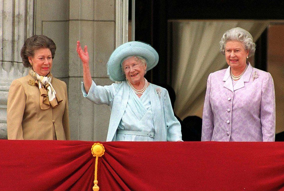 Princess Margaret (L) and Queen Elizabeth (R) stand next to the Queen Mother as she waves to admirers on the occasion of her 100th birthday celebration 4 August, 2000 in London.