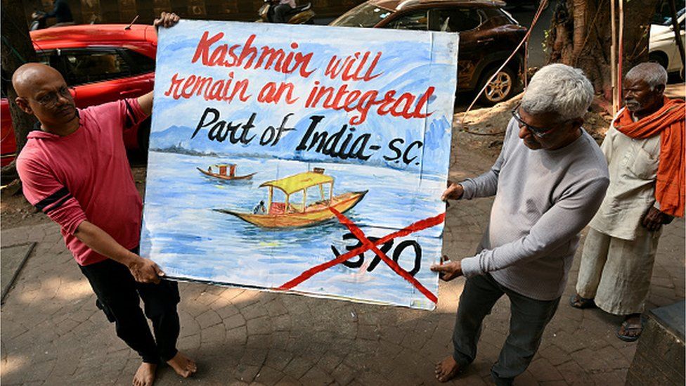 An art school teacher carries a painting depicting the Supreme Court's verdict on Article 370, in Mumbai on December 11, 2023.