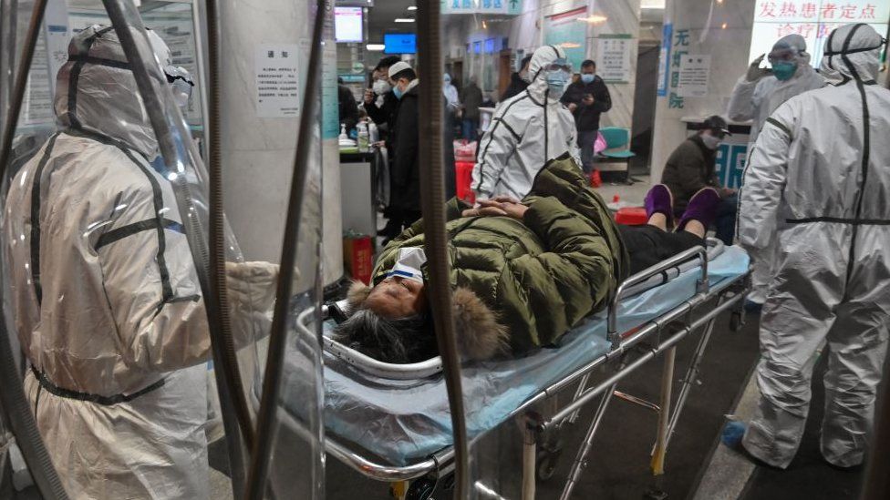 Miembros del personal médico con ropa protectora para ayudar a detener la propagación de un virus mortal que comenzó en la ciudad, llegan con un paciente en el Hospital de la Cruz Roja de Wuhan en Wuhan el 25 de enero de 2020.