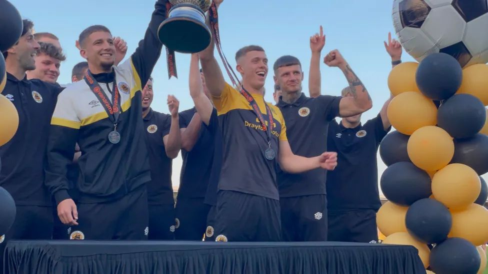 Boston United players lifting the trophy