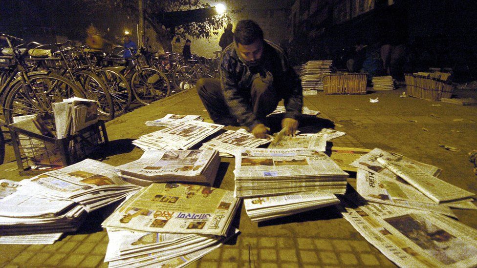 A newspaper vendor arranging stacks of newspapers