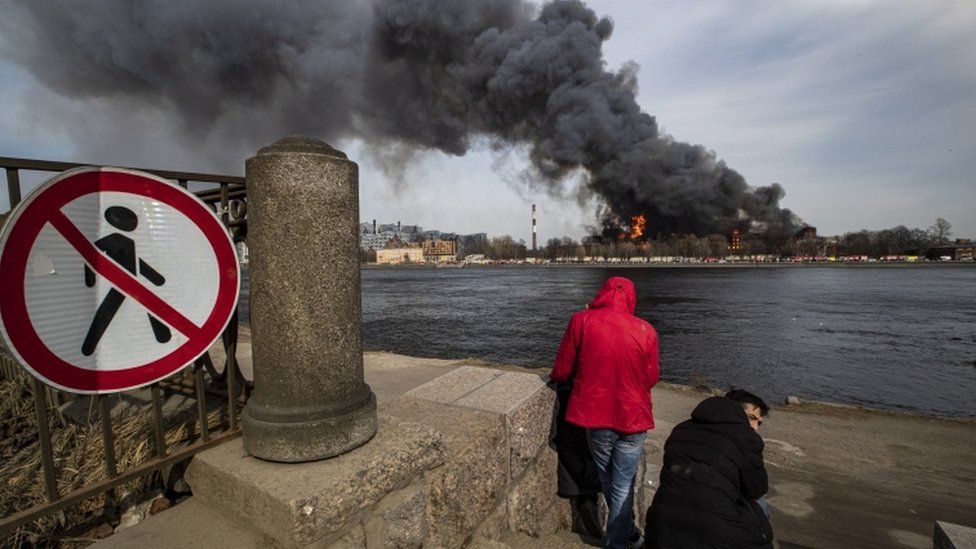 Two people watching smoke from across a river