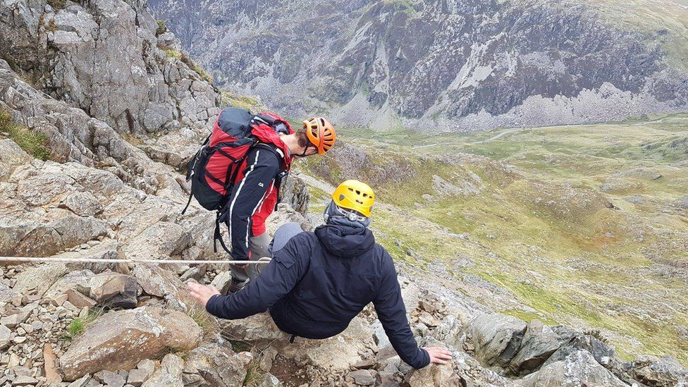Two men winching themselves down a gorge in Snowdonia