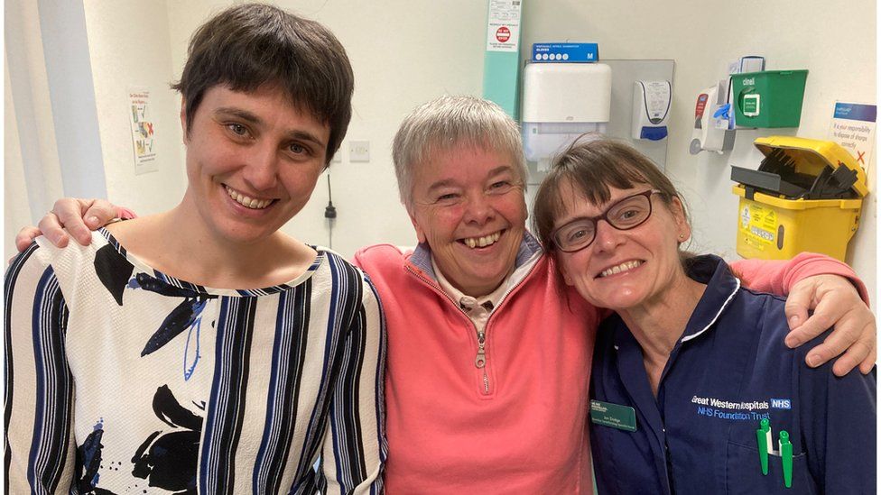 Mo Squires with her arms around her medical team: Lead Gynae Oncology Consultant Amy Keightly and Specialist Cancer Nurse, Jan Dodge at Swindon's Great Western Hospital