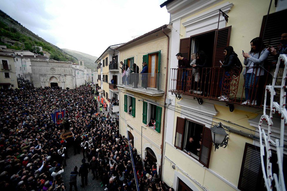 People watch from a balcony as a statue of Saint Domenico covered with live snakes is carried by faithfuls during an annual procession in the streets of Cocullo