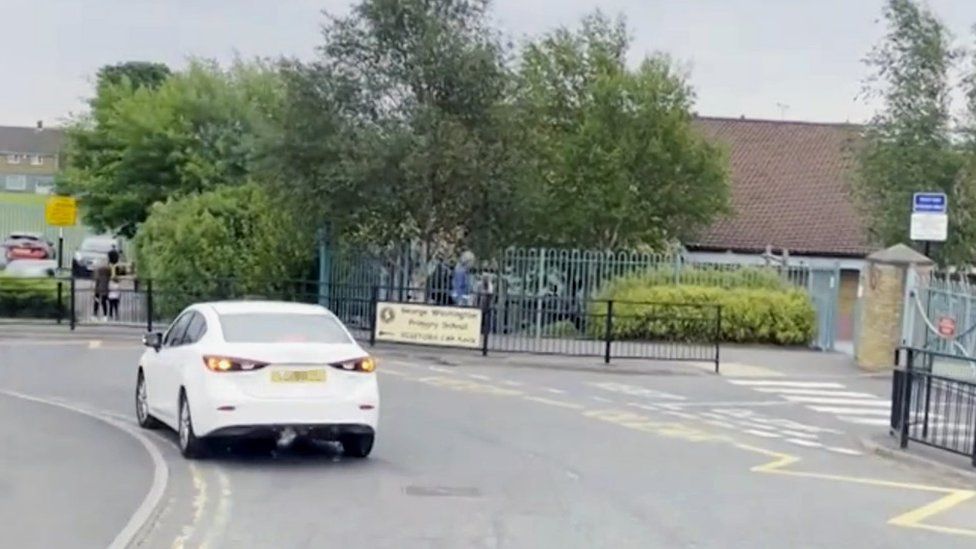 Car parked on double yellow lines outside a school