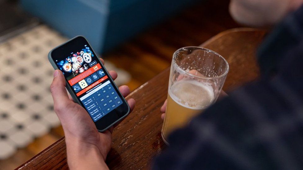Man gambling on smartphone in pub (stock image)