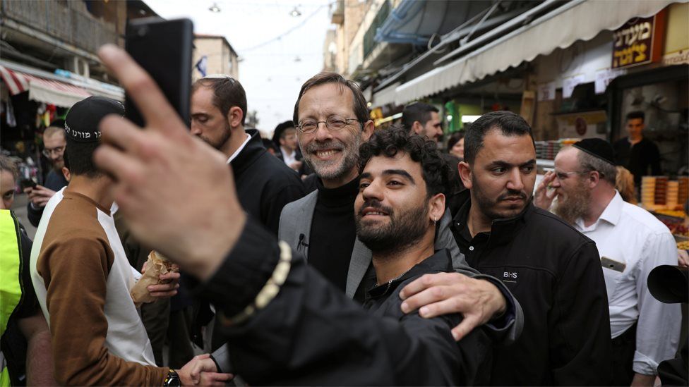 Zehut party leader Moshe Feiglin (C) poses for a selfie with a man at a market in Jerusalem on 4 April 2019