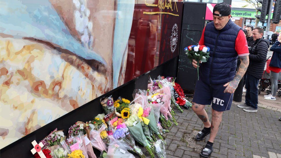 Man laying flowers on Shankill Road for Queen