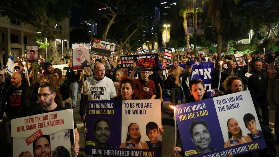 Hundreds of people march through central Tel Aviv. They are seen holding placards calling on the Israeli government to secure the release of hostages held in Gaza.